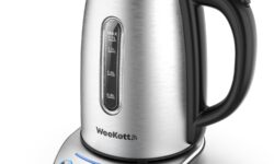 A tall cylindrical silver plastic Kettle with a Black Plastic Handle that has WeeKett written in bold black writing on it on top of a large circular metallic silver base that has six silver buttons and some bright blue lights on it, on a white background.