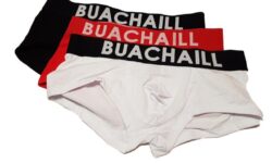 A pair of black, red and white folded up boxers with a black waistband that has Buachaill written in bold white writing on it, on a white background.