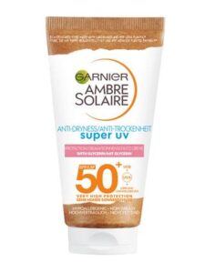 A short conical white plastic tube that has Garnier written in bright blue writing, Ambre Solaire Anti-Dryness Super UV Protection Cream written in bold black writing, SPF50+ written in bold gold writing, and a picture of a gold stripe on it, on a white background.