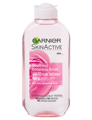 A tall rounded rectangular pale pink plastic bottle with a white Plastic lid that has Garnier Naturals Rose Water Toner For Sensitive Skin written in bold black writing and a picture of a large bright pink rose on it, on a white background.