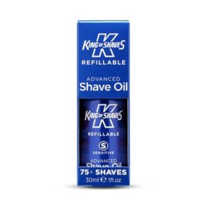 A short cylindrical metallic dark blue bottle with a clear plastic lid that has King of Shaves Refillable Advanced Sensitive Shave Oil written in bold white writing on it, on a white background.