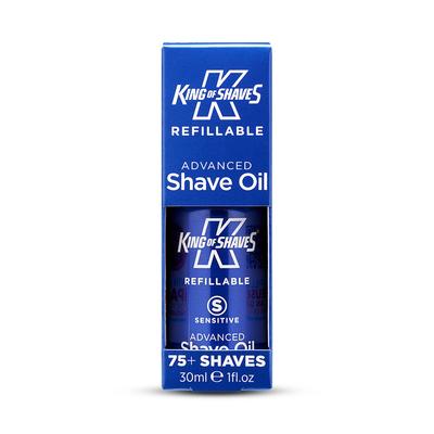 The Bluebeards Revenge Cooling Moisturiser, Luxury Shaving Cream, and Post Shave Balm A short cylindrical metallic dark blue bottle with a clear plastic lid that has King of Shaves Refillable Advanced Sensitive Shave Oil written in bold white writing on it, on a white background.