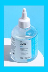 A large spherical clear plastic bottle full of some clear liquid with a white plastic dropper lid and a white label that has Primark PS Futures Bright 5% Glycolic Toner written in bold black writing and a picture of a bright blue stripe on it, on a white background.