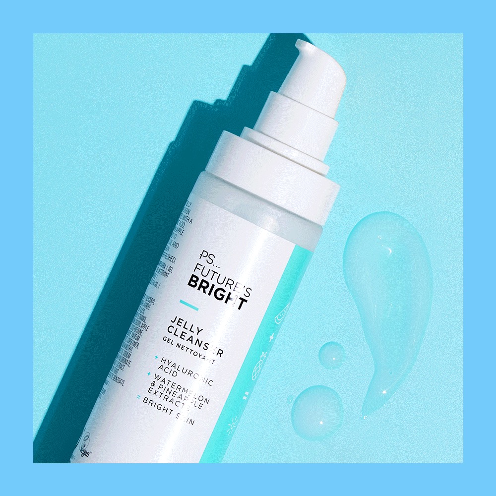 A tall cylindrical clear plastic bottle full of some clear liquid with a white plastic pump lid and a white label that has Primark PS Futures Bright Jelly Cleanser written in bold black writing and a picture of a bright blue stripe on it, on a white background.