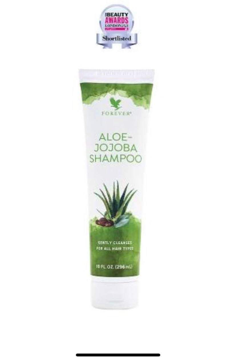 A tall cylindrical White Plastic Bottle with a white plastic lid and a white label that has Forever Living Aloe Jojoba Shampoo written in bright green writing and some pictures of some large dark green aloe vera leaves on it, on a white background.