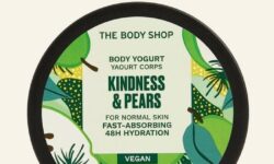A short rounded rectangular black plastic tub with a black plastic lid that has The Body Shop written in bold black writing, Kindness & Pears Body Yoghurt written in bold dark green writing, and some pictures of some large bright green pears on it, on a white background.
