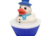 A large cylindrical bright white cupcake shaped block of soap that has a bright blue pond design and a small bright white rubber duck wearing a bright blue hat and scarf on top of it, on a white background.
