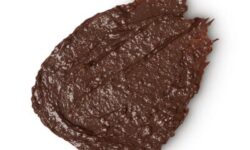 A medium circular puddle of dark brown body wash, on a white background.