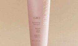 A tall conical bright pink Plastic Tube with a bright pink lid that has Vegamour Grow Revitalising Shampoo written in bold gold writing on it, on a white background.