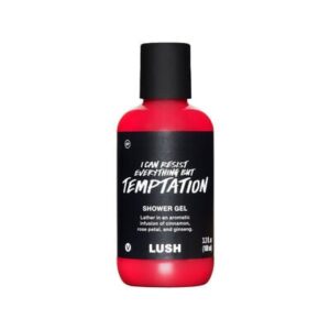 A tall cylindrical clear plastic bottle full of some dark red liquid with a black plastic lid and a black label that has Lush Temptation Shower Gel written in bold white writing on it, on a white background.