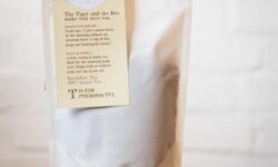 A tall rectangular white paper pouch with a cream label that has Two Chimps Coffee Breakfast Loose Leaf Tea written in bold black writing and a picture of a large black and orange striped Tiger on it, on a white background.