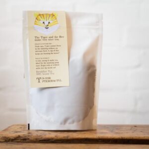 A tall rectangular white paper pouch with a cream label that has Two Chimps Coffee Breakfast Loose Leaf Tea written in bold black writing and a picture of a large black and orange striped Tiger on it, on a white background.