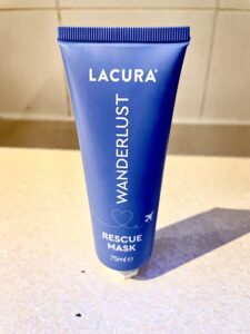A tall conical bright turquoise plastic tube with a white plastic lid that has Aldi Wonderlust Rescue Mask written in bold white writing on it, on a white background.