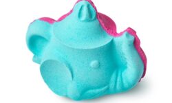 A large gradient bright blue and purple teapot shaped bath bomb that has some large dark brown eyes engraved on it, some light blue elephant tusks, and an elephant’s trunk for a spout on it, on a white background.