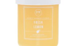 A tall cylindrical clear glass jar full of some bright yellow wax with a white plastic lid and a bright yellow label that has DW Home Candles Fresh Lemon written in bold white writing on it, on a white background.