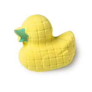 A large bright yellow duck shaped bath bomb that has a bright green beak and some bright green lines all over it, on a white background.