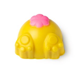 A large bright yellow rabbit’s behind shaped block of solid body scrub that has two bright yellow paws coming out of the bottom of it and a bright pink fluffy tail engraved on it, on a white background.