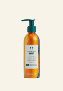 A tall cylindrical metallic Orange Aluminium Bottle with a Silver Aluminium lid and a white label that has The Body Shop Boost Uplifting Hair & Body Wash written in dark green writing and some pictures of some bright Orange swirls on it, on a white background.