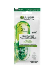 A tall rectangular white plastic pouch that has Garnier SkinActive Niacinamide Detox Ampoule Sheet Mask written in bold black writing and a picture of a large gradient bright green Tablet on it, on a white background.