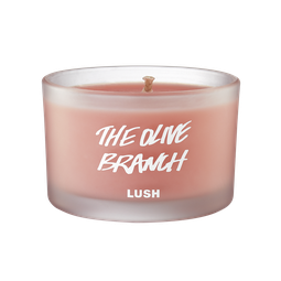 A short cylindrical frosted glass jar full of some pale pink wax, on a white background.