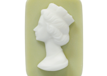 A large rectangular pale blue block of soap that has a picture of a bright white woman wearing a crown engraved on it, on a white background.