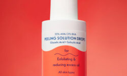 A short cylindrical white plastic bottle with a white rubber pipette lid that has By Beauty Bay 30% AHA / 2% BHA Peeling Solution with Glycolic Acid and Salicylic Acid written in bold dark blue writing and a picture of a bright orange wave on it, on a bright orange background.