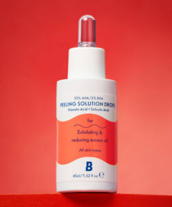 A short cylindrical white plastic bottle with a white rubber pipette lid that has By Beauty Bay 30% AHA / 2% BHA Peeling Solution with Glycolic Acid and Salicylic Acid written in bold dark blue writing and a picture of a bright orange wave on it, on a bright orange background.