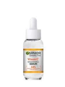 A short cylindrical translucent green glass bottle with a white rubber pipette lid that has Garnier Vitamin C Anti-Dark Spot & Brightening Serum written in bold black writing on it, on a white background.