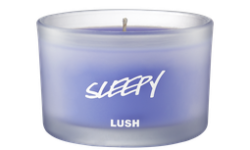 A short cylindrical frosted glass jar full of some pale lilac wax, on a white background.