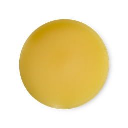 A medium circular puddle of some bright orange solid perfume, on a white background.