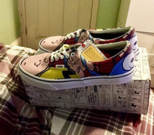 A pair of white canvas trainers with some bright white laces that has some bright blue spots, some bright red spots, and some pictures of a boy’s face on them, on a white background.