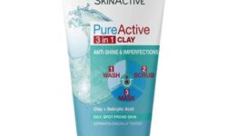 A tall conical white plastic tube with a White Plastic Lid that has Garnier written in bold black writing, Pure Active written in dark blue writing, Clay Wash Scrub Mask Oily Skin written in bright red writing, a picture of a dark blue stripe, and a picture of a puddle of water on it, on a white background.