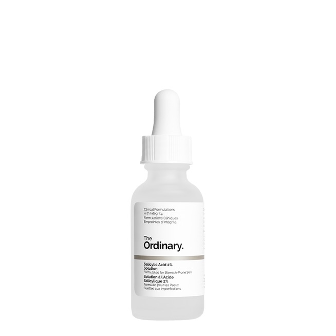 A short cylindrical clear glass Bottle with a white rubber pipette lid full of some bright white liquid with a white label that has the ordinary salicylic acid 2% solution written in bold black writing on it, on a white background.