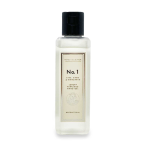 A tall rectangular glass bottle with a black plastic lid and a white label that has Aldi Hotel Collection Lime, Basil & Mandarin Luxury Perfumed Antibacterial Hand Gel written in bold black writing on it, on a white background.