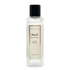 A tall rectangular glass bottle with a black plastic lid and a white label that has Aldi Hotel Collection Pomegranate Luxury Perfumed Antibacterial Hand Gel written in bold black writing on it, on a white background.