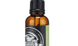 A short cylindrical brown glass bottle with a black rubber pipette lid and a white label that has Arthur J Hawke Tropical Punch Beard Oil written in bold white writing and a picture of a black and white hawk on it, on a white background.