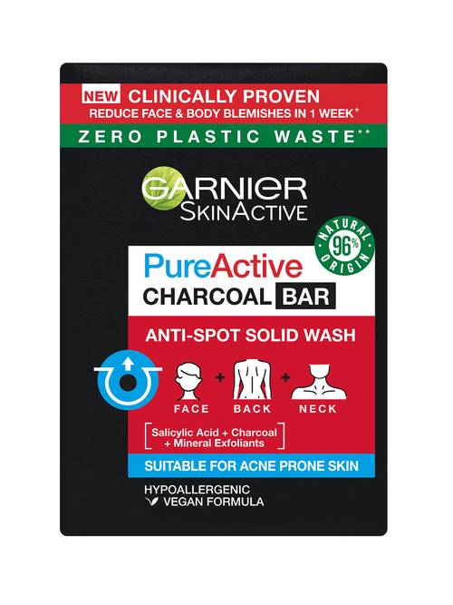A large rectangular bar of soap wrapped in some black paper that has Garnier written in bold white writing, Pure Active Anti-Spot and Blackhead Solid Wash Charcoal Bar written in bold black writing, and a picture of a Red box on it, on a white background.
