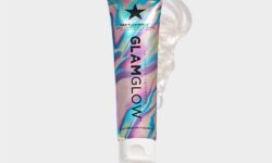 A tall conical metallic rainbow effect blue, Pink and purple plastic tube with a white plastic lid that has GlamGlow GentleBubble™ Daily Conditioning Cleanser written in bold black writing and a picture of a black star on it, on a white background.