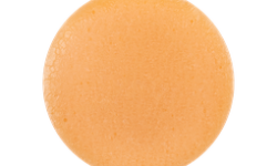A medium circular puddle of some dark orange toothpaste jelly, on a white background.