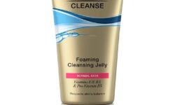 A tall conical bright yellow plastic tube with a clear plastic lid that has Olay Cleanse Foaming Cleansing Jelly written in bold black writing on it, on a white background.