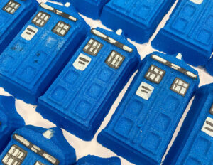 A large rectangular dark blue time machine shaped bath bomb that has some bright white windows and police box written in bold white writing engraved on it, on a white background.
