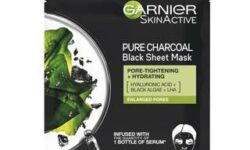 A tall rectangular black plastic pouch that has Garnier SkinActive Moisture Bomb Charcoal & Algae Hydrating Sheet Mask written in bright white writing and a picture of some dark green leaves on it, on a white background.