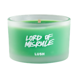 A short cylindrical frosted glass jar full of some bright green wax, on a white background.