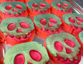 One Bath With A Poisoned Apple And The Victim’s Eyes Will Close Forever | Tales Of Toria Halloween 2022 Range A large gradient bright green and red apple shaped bath bomb that has a gold skull face engraved on it, on a white background.