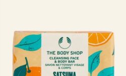 A large rectangular block of Soap wrapped in some bright white paper that has The Body Shop Satsuma Cleansing Face & Body Bar written in bold black writing and some pictures of some bright orange satsumas on it, on a white background.