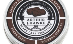 A short cylindrical white metallic tin with a gradient black and white metallic lid and a white label that has Arthur J Hawke Chocolate Bourbon Beard Balm written in bold black writing and a picture of a black hawk on it, on a white background.