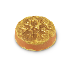 Lighting Up The World From Inside My Bathroom | Lush Diwali 2022 Range A large circular bright yellow and orange Bath Bomb that has an intricate diamond pattern and some gold Lustre embedded on it, on a white background.