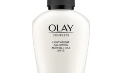 A short teardrop shaped clear plastic bottle full of some creamy white liquid with a black plastic lid and a clear label that has Olay Complete Lightweight 3 in 1 Day Fluid SPF15 written in bold black writing on it, on a white background.