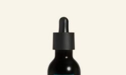 A short cylindrical clear glass bottle full of some black liquid with a black rubber pipette lid and a light blue label that has The Body Shop Himalayan Charcoal Skin Clarifying Night Peel written in bold black writing on it, on a white background.