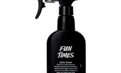 A tall black plastic kitchen spray bottle that has Lush Fun Times Body Spray written in bold white writing on it, on a white background.